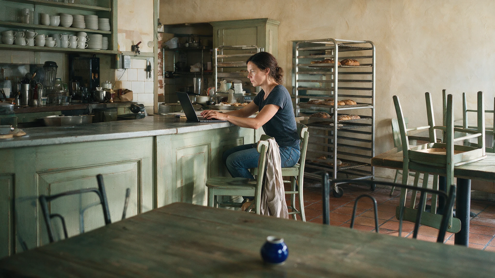 Propietaria de una panadería trabajando con un portátil antes de abrir al público