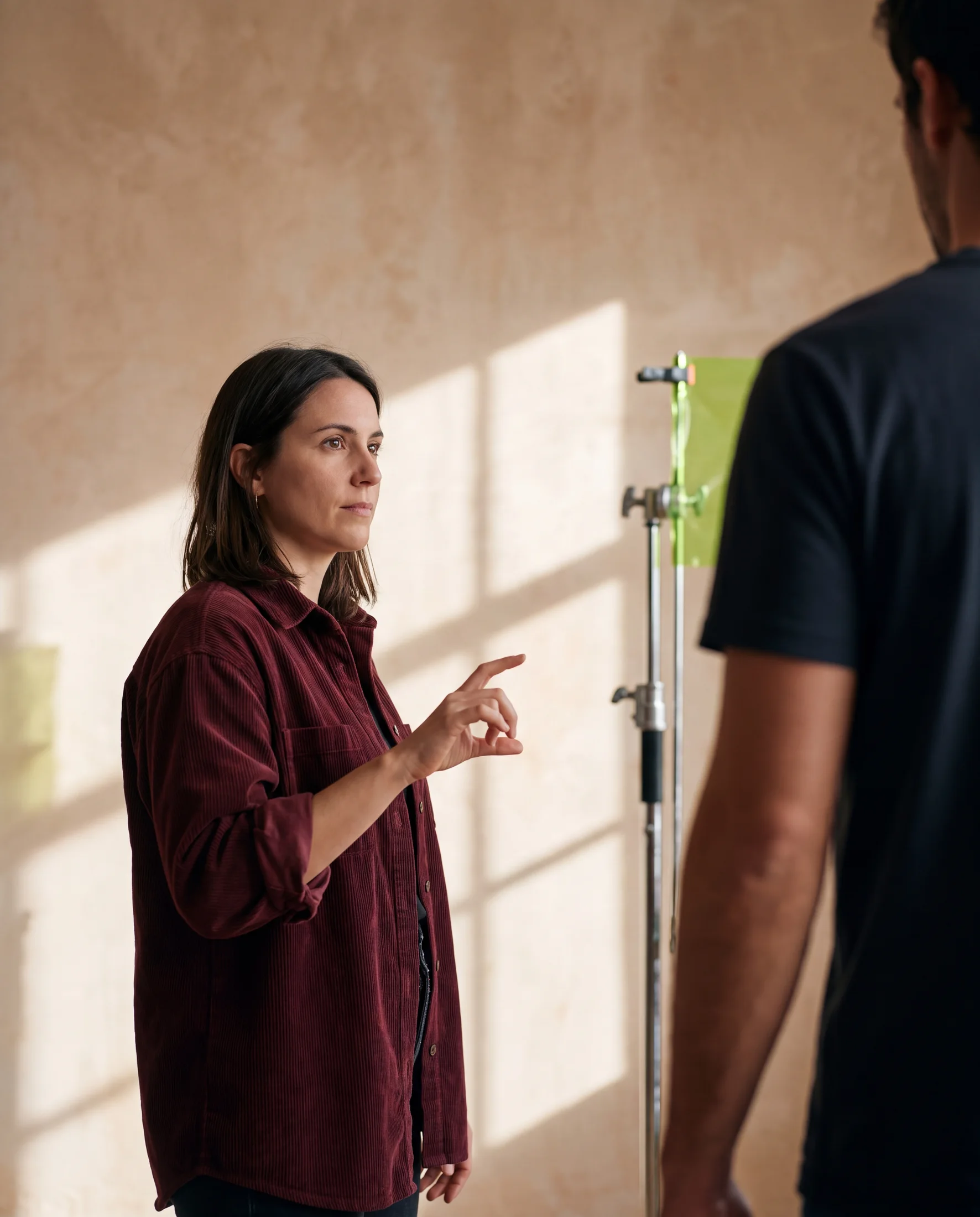 A creative director guides a production decision in a warm daylight studio